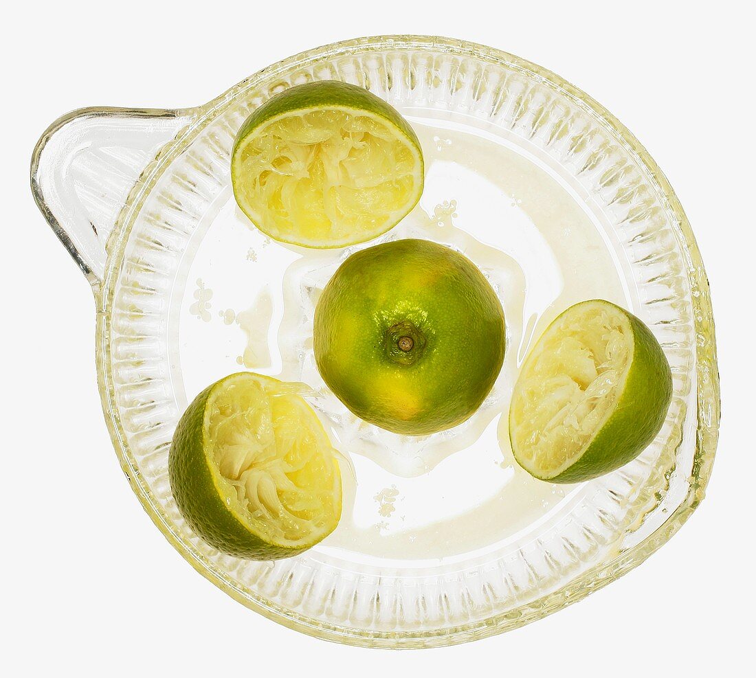 Limes on lemon squeezer on green wooden background