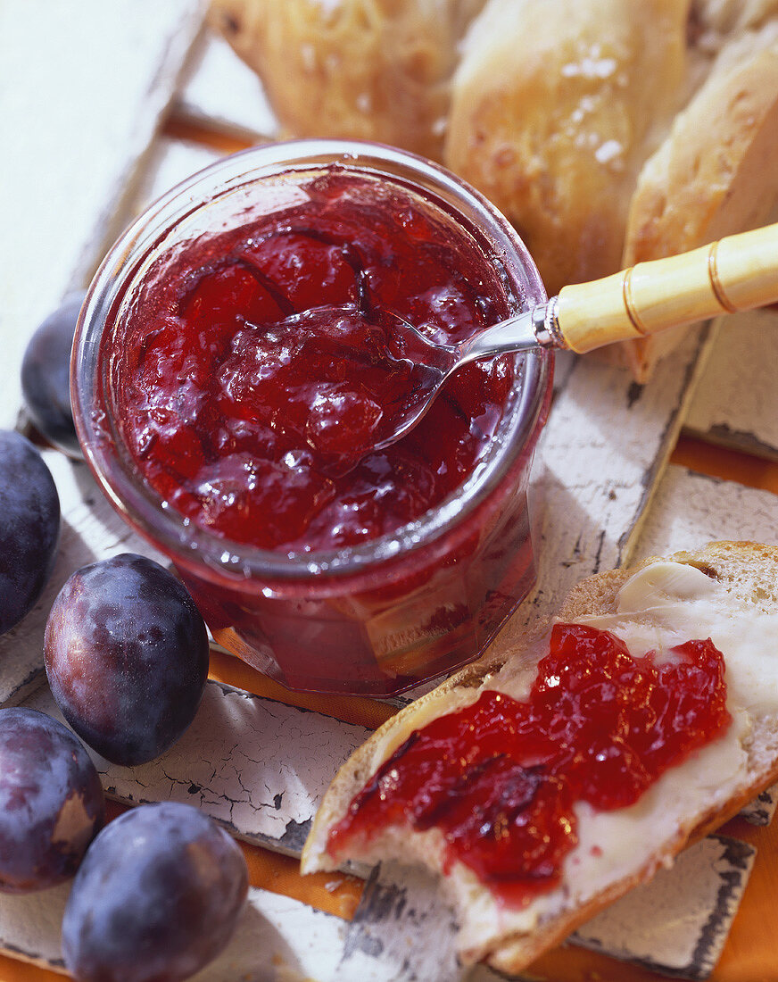Plum jam in jar and a piece of bread and jam