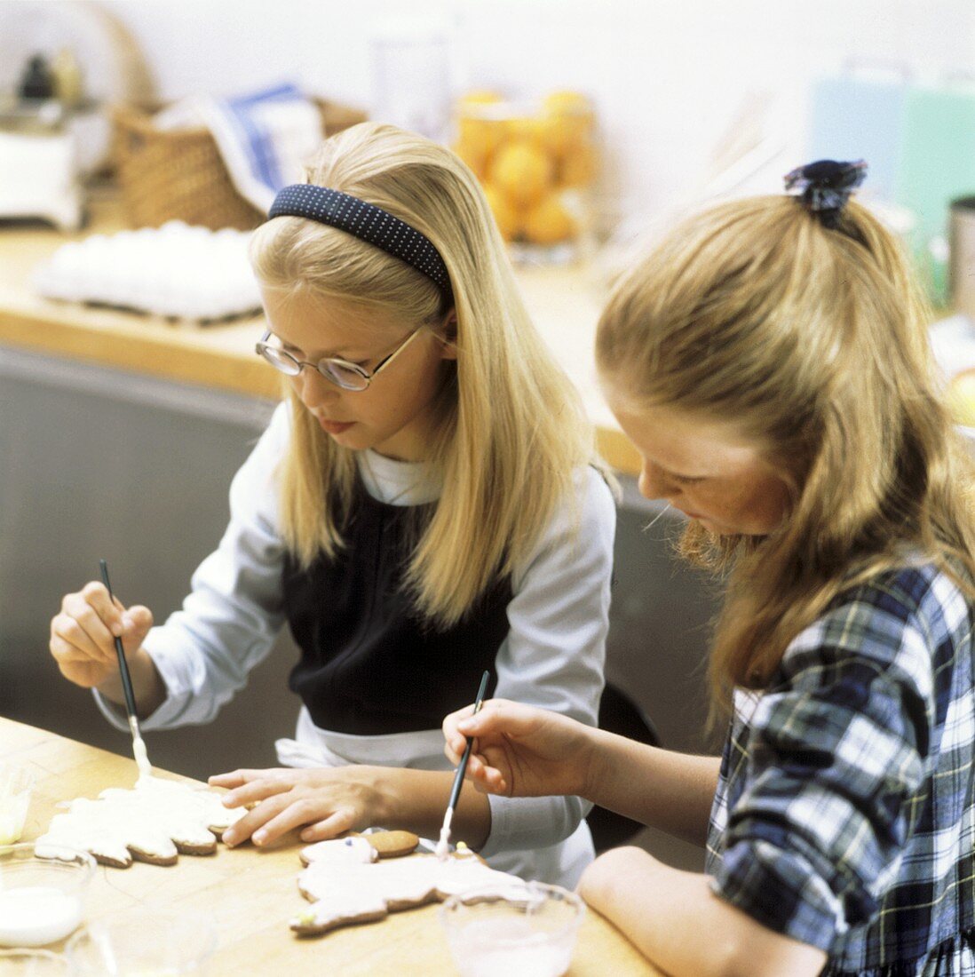 Two girls painting Christmas biscuits