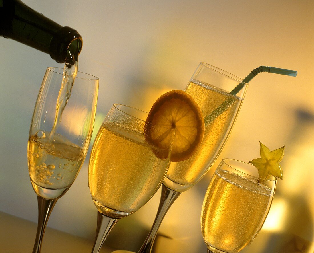 Four glasses of champagne (some decorated with fruit slices)