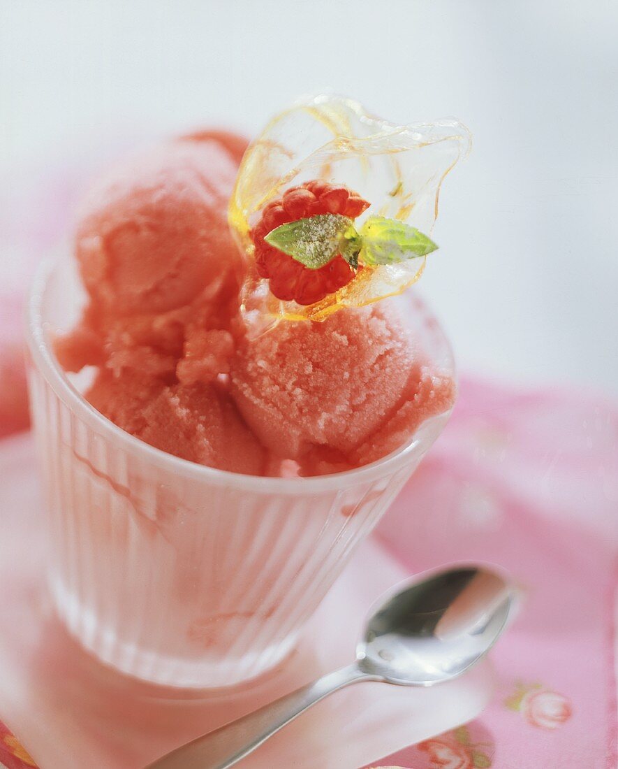 Mehrere Kugeln Himbeersorbet in einem Glasbecher