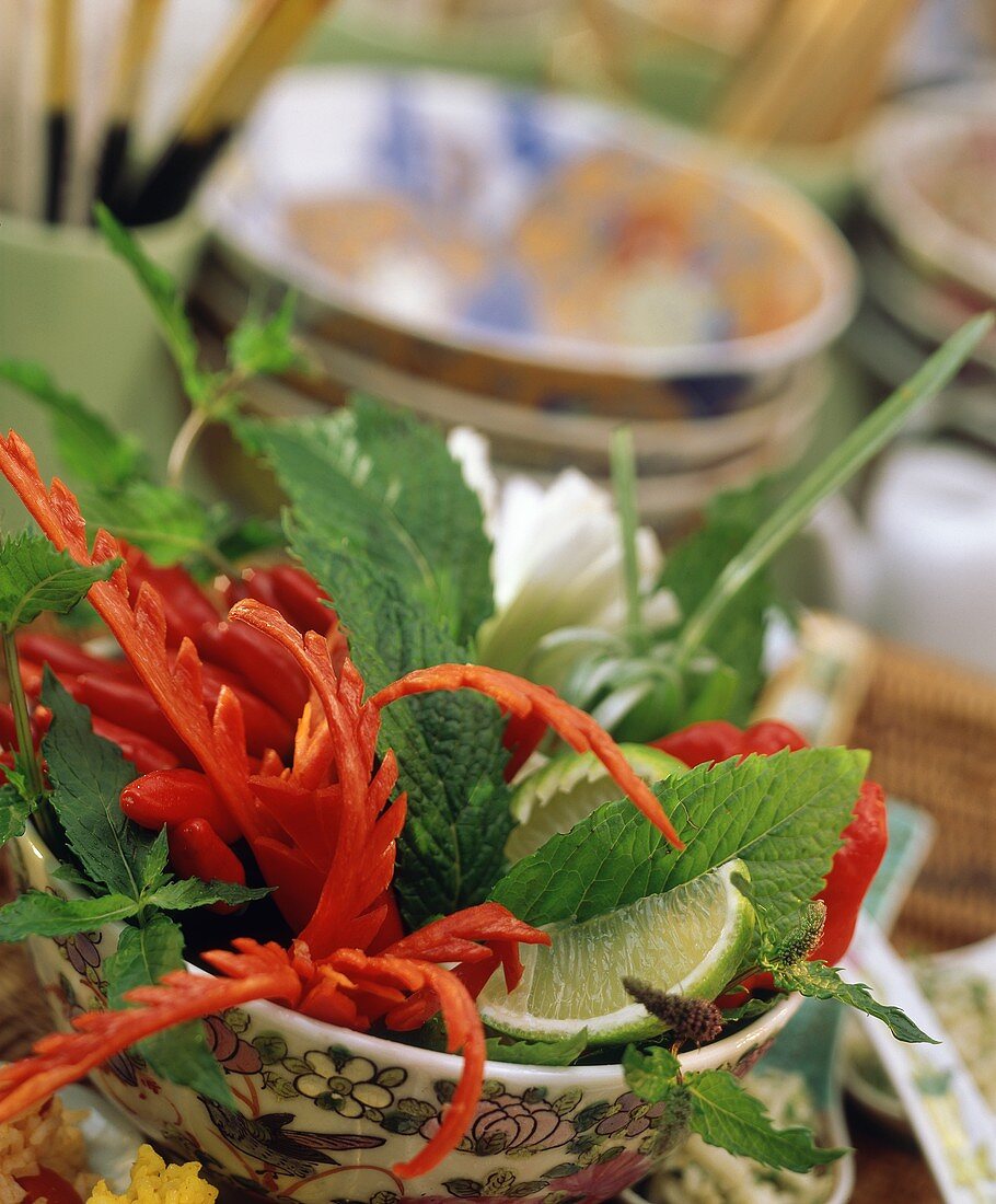 Asiatische Tischdeko mit Kräutern und geschnitzten Peperoni