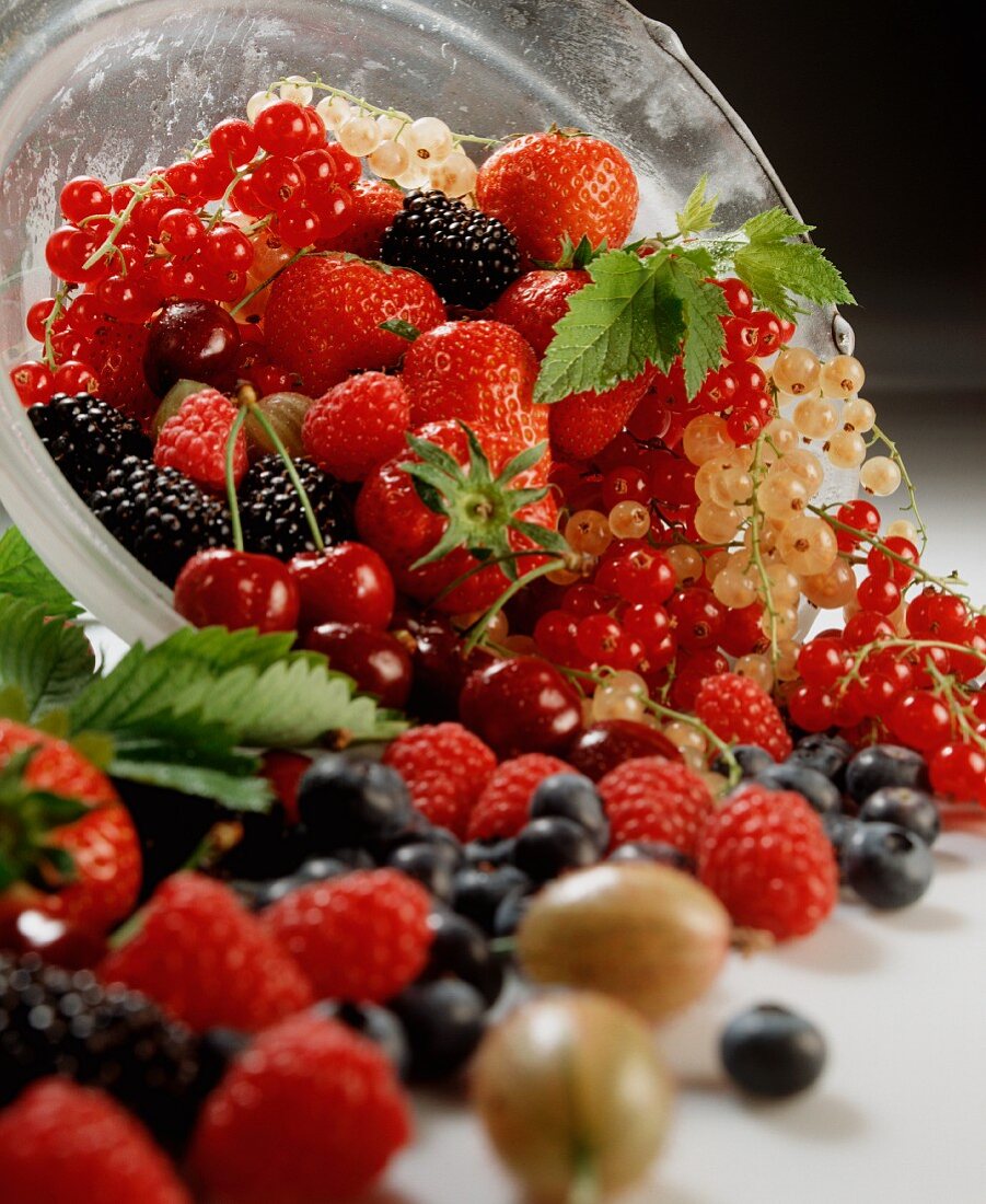 Fresh berries and cherries in a dish and in front of it