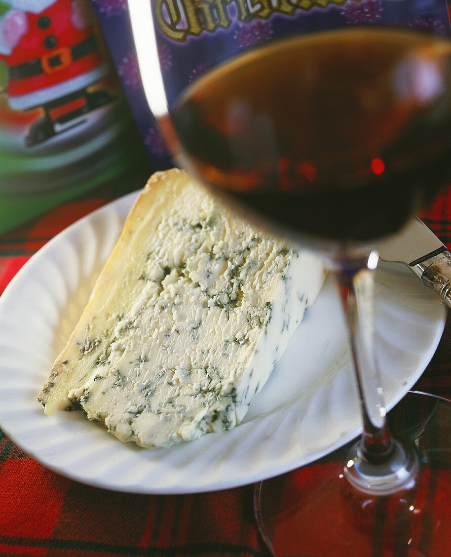 A piece of blue cheese on a plate and a glass of wine
