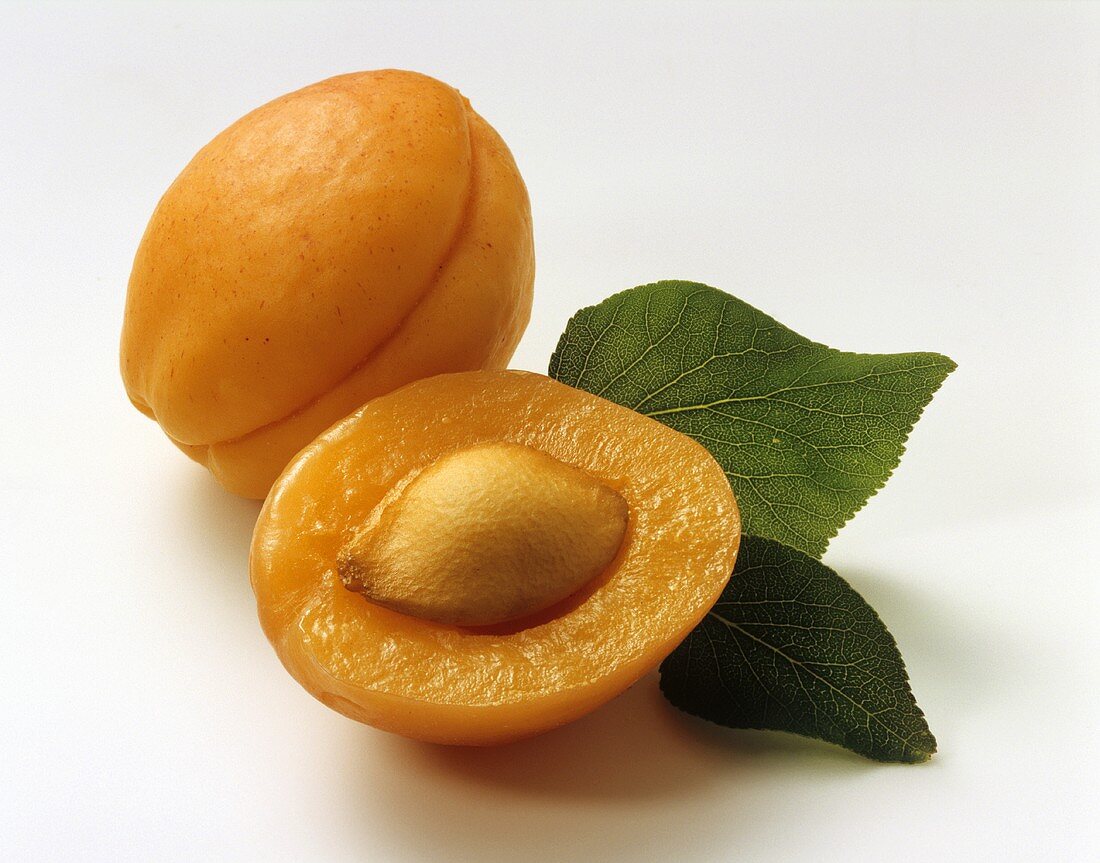 One half and one whole apricot with leaves