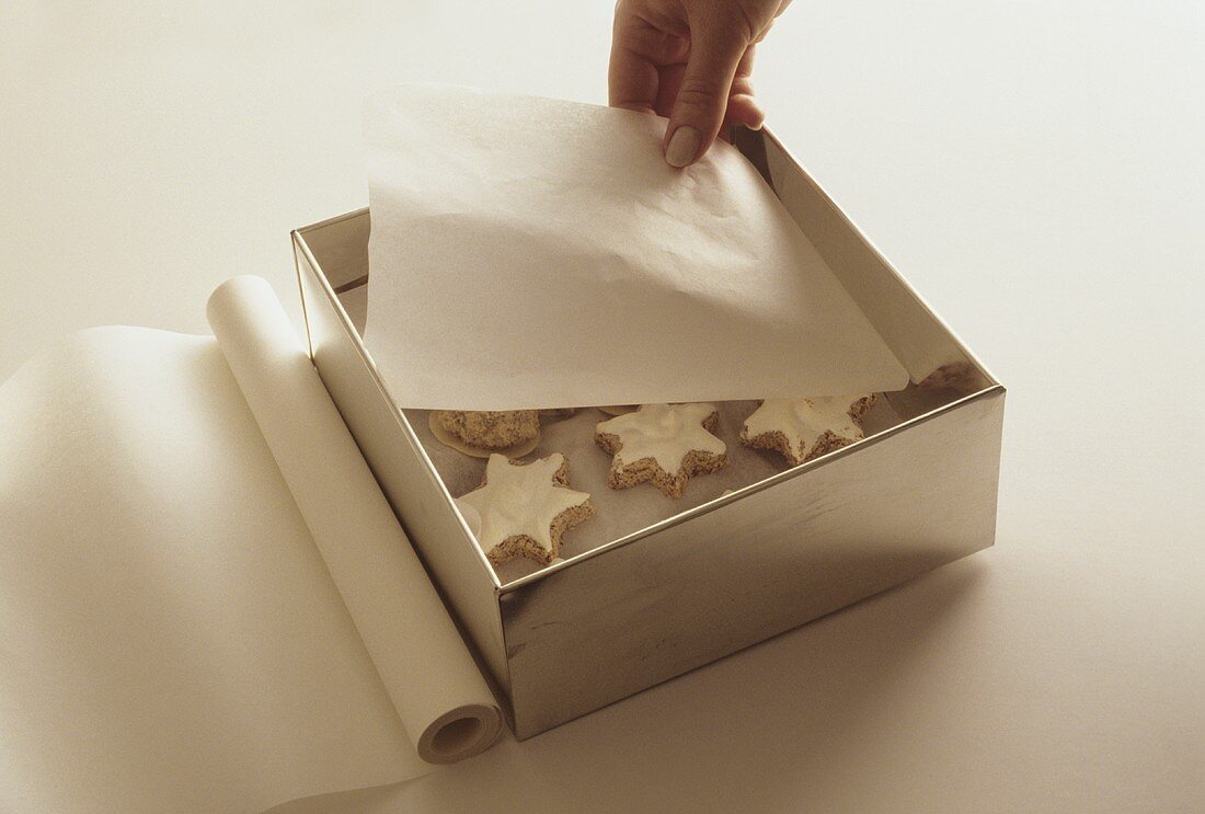 Zimtsterne mit Pergamentpapier in einer Blechdose