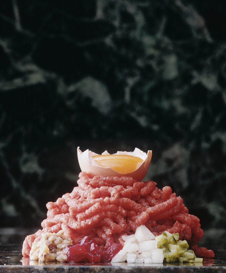 Beef tartar with ingredients on a marble platter