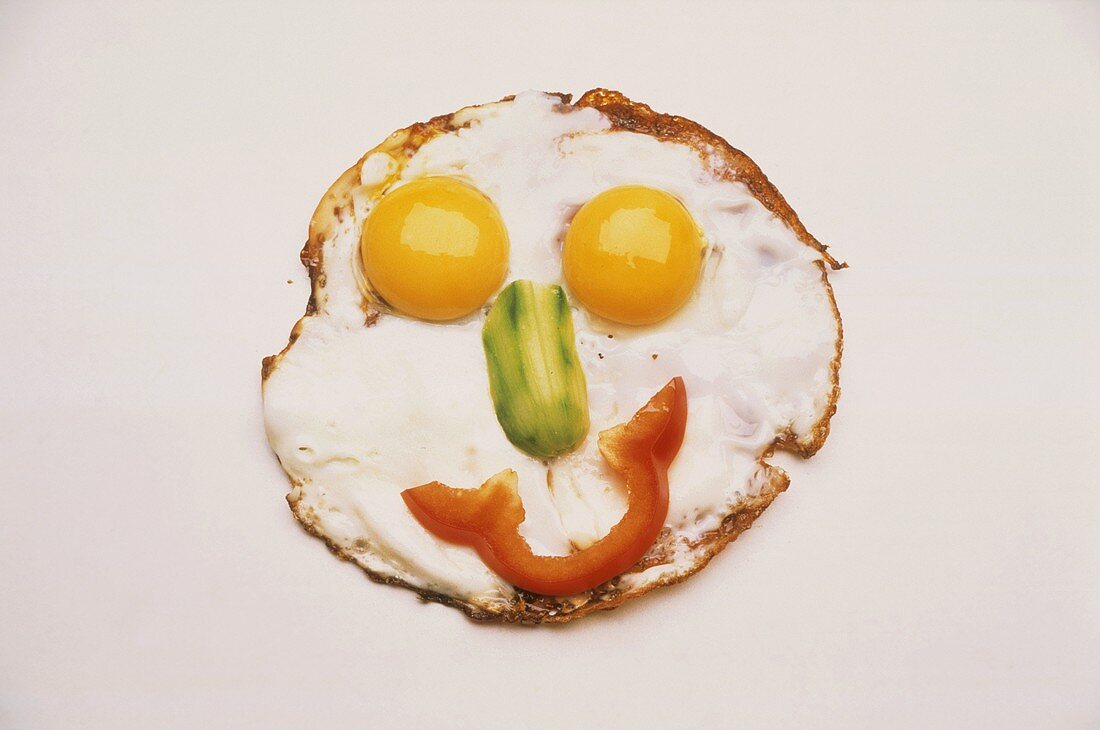 Fried egg face with gherkin nose and pepper mouth