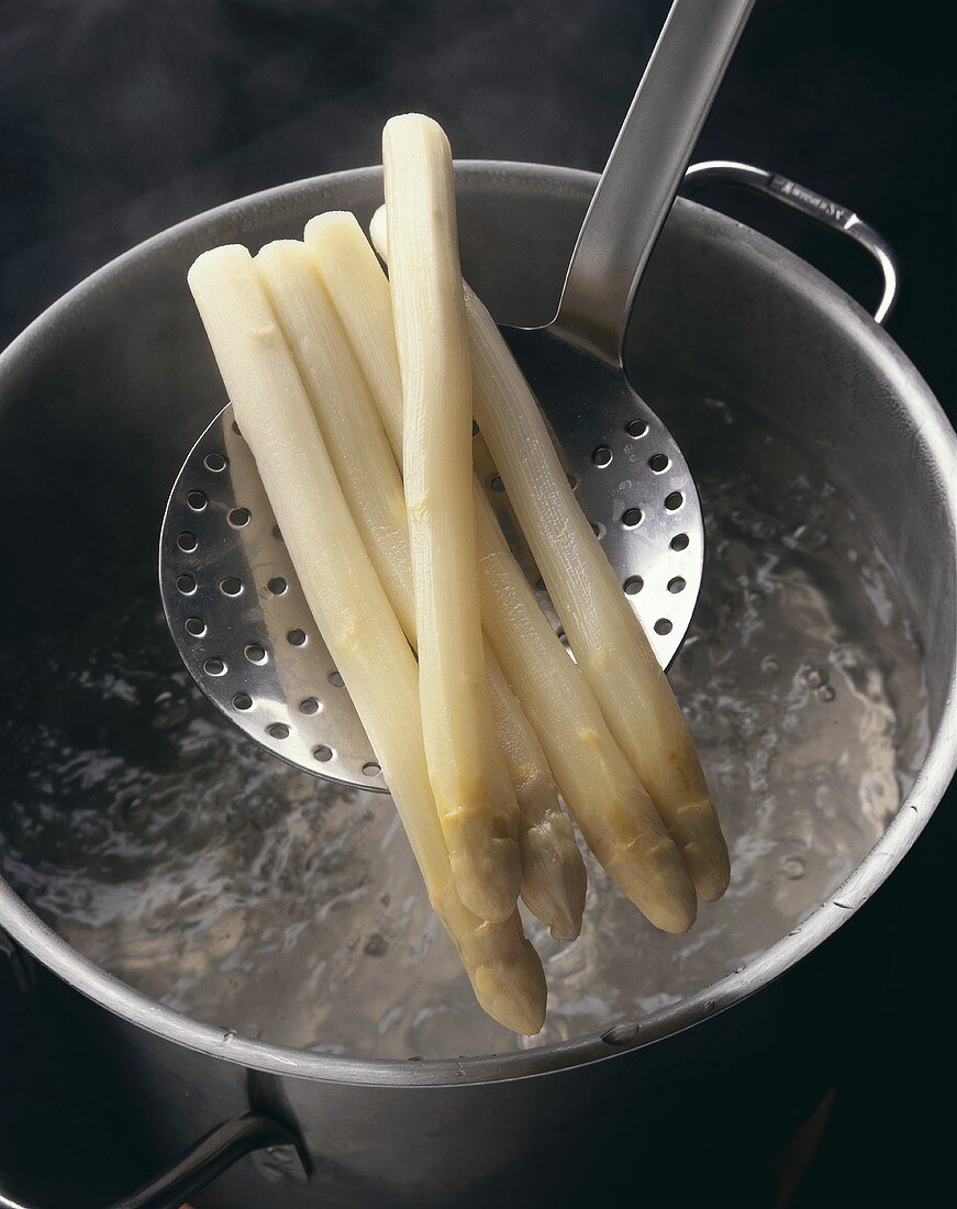 White asparagus on a skimmer over boiling water