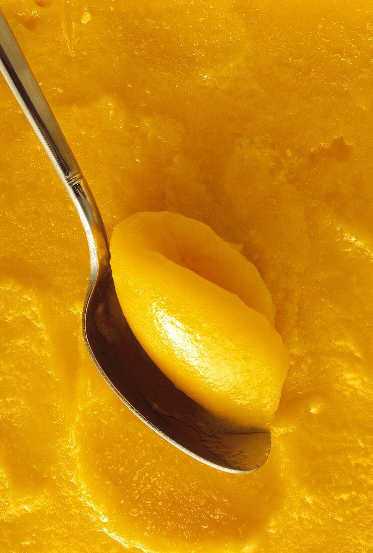 Mango sorbet with spoon (close-up)