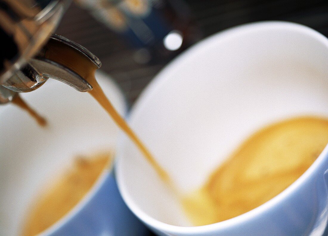 Cappuccino running out of the machine into two cups