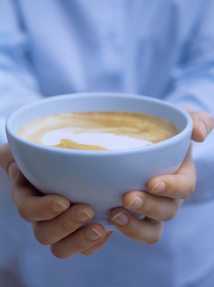 Hände halten Schälchen mit Milchkaffee