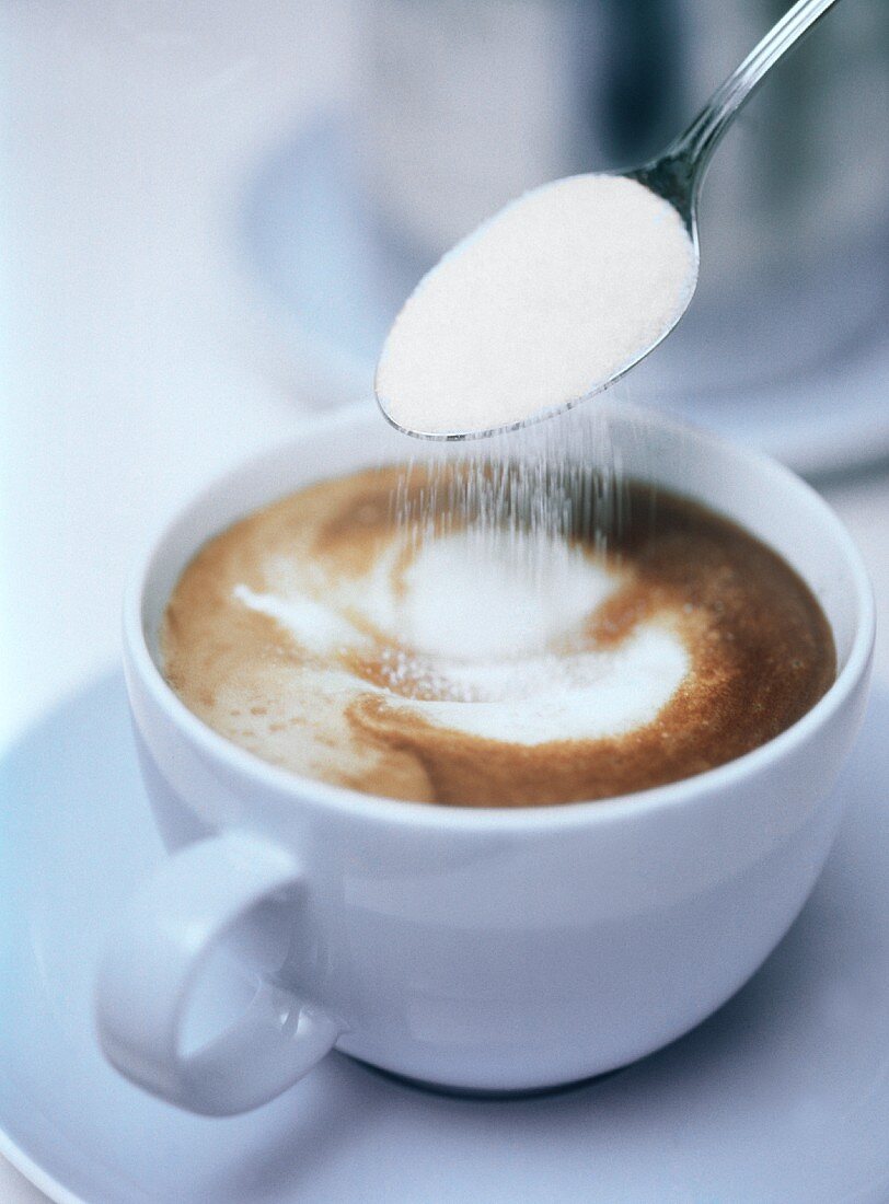 Sprinkling sugar into cappuccino