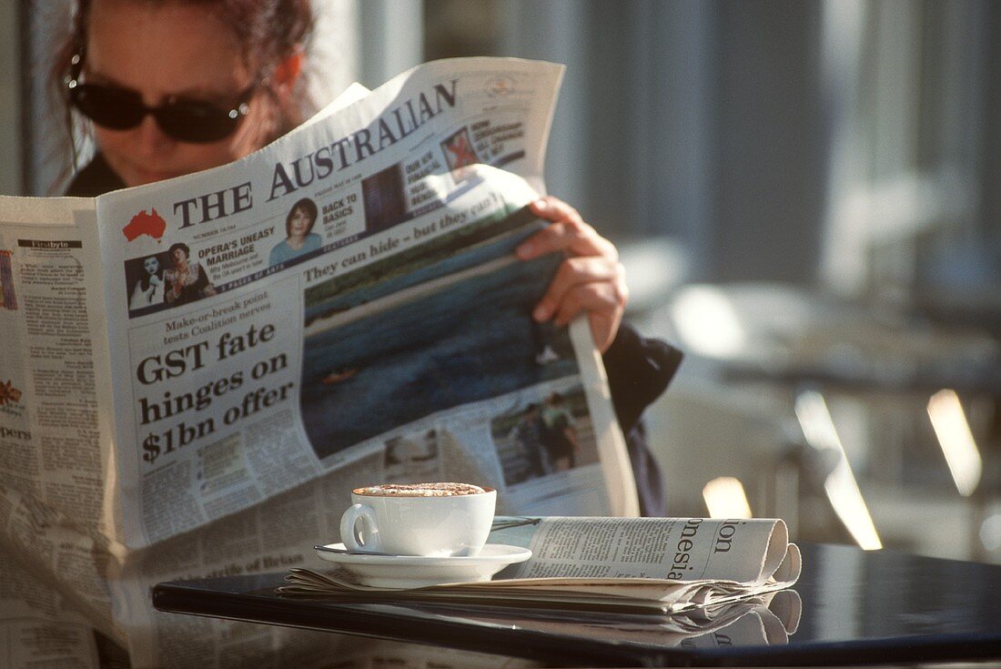 Young woman reading Australian newspaper (café in Sydney)