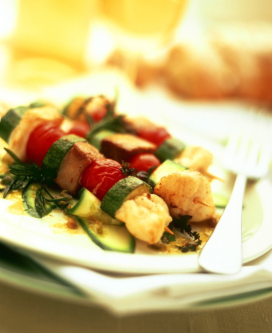 Fish and vegetable kebabs on courgette salad