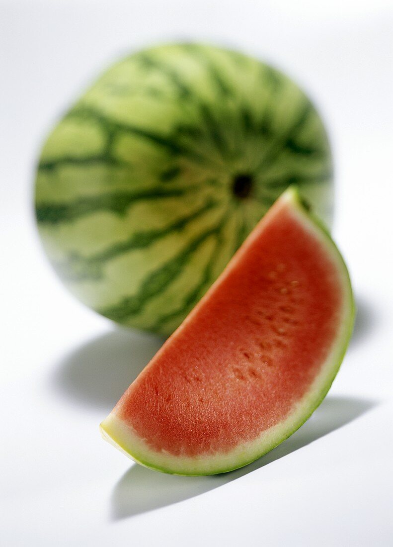 Eine ganze Wassermelone und ein Melonenschnitz
