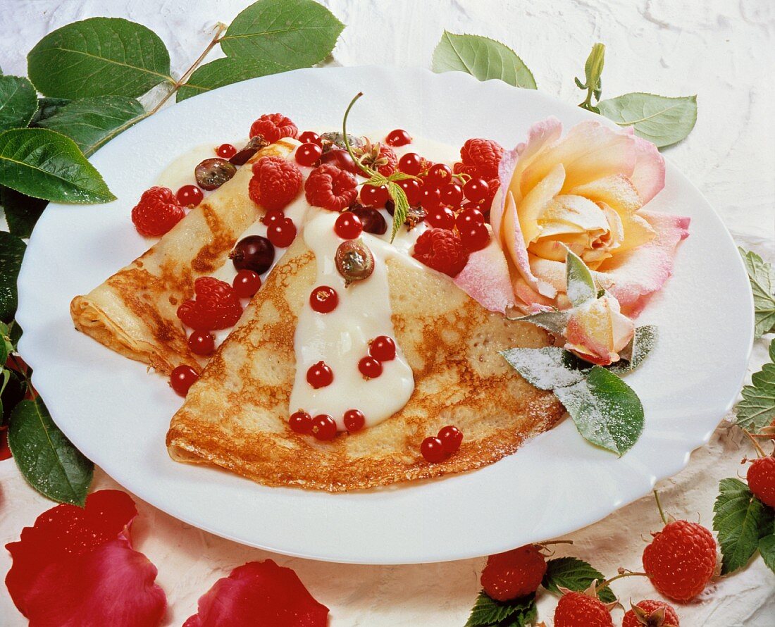 Pancakes with berries, vanilla sauce and candied roses