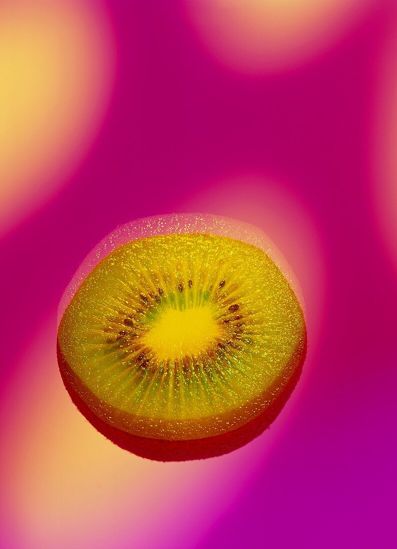 A slice of kiwi fruit against pink background (surreal)