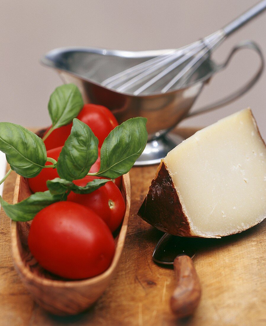 Frische Tomaten, Basilikum und Stück Käse; Sauciere