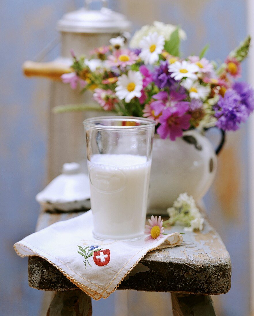 Stillleben mit Milch aus der Schweiz, Serviette und Blumen