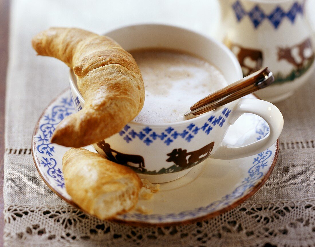 Croissant on a cup of milky coffee