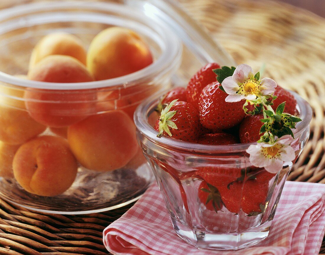 Fresh apricots and strawberries in glass jars