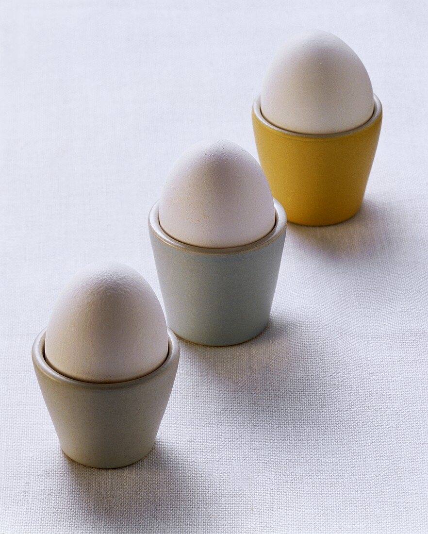 Drei gekochte Eier in Eierbechern