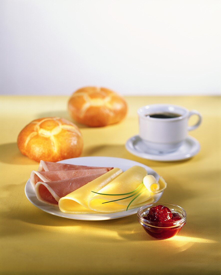 Frühstück mit Käse, Schinken, Marmelade, Brötchen und Kaffee