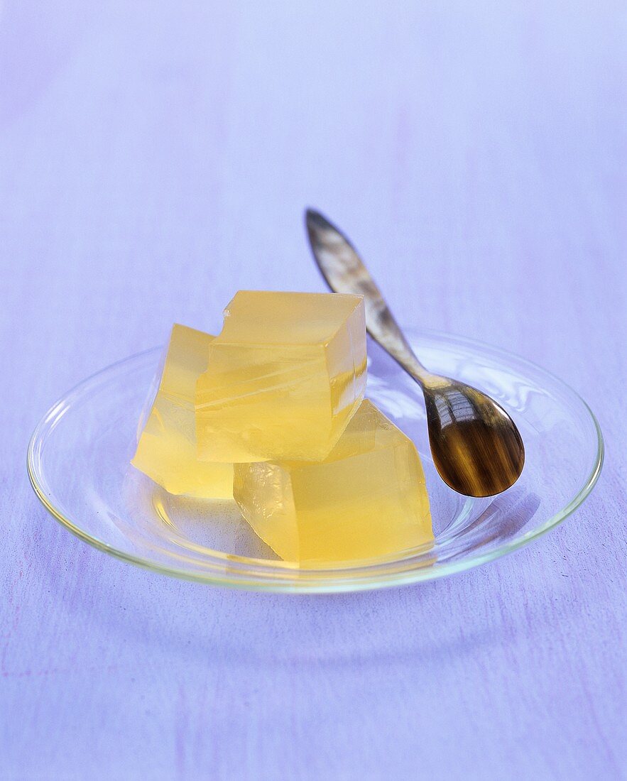 Three cubes of apple jelly on glass plate with spoon