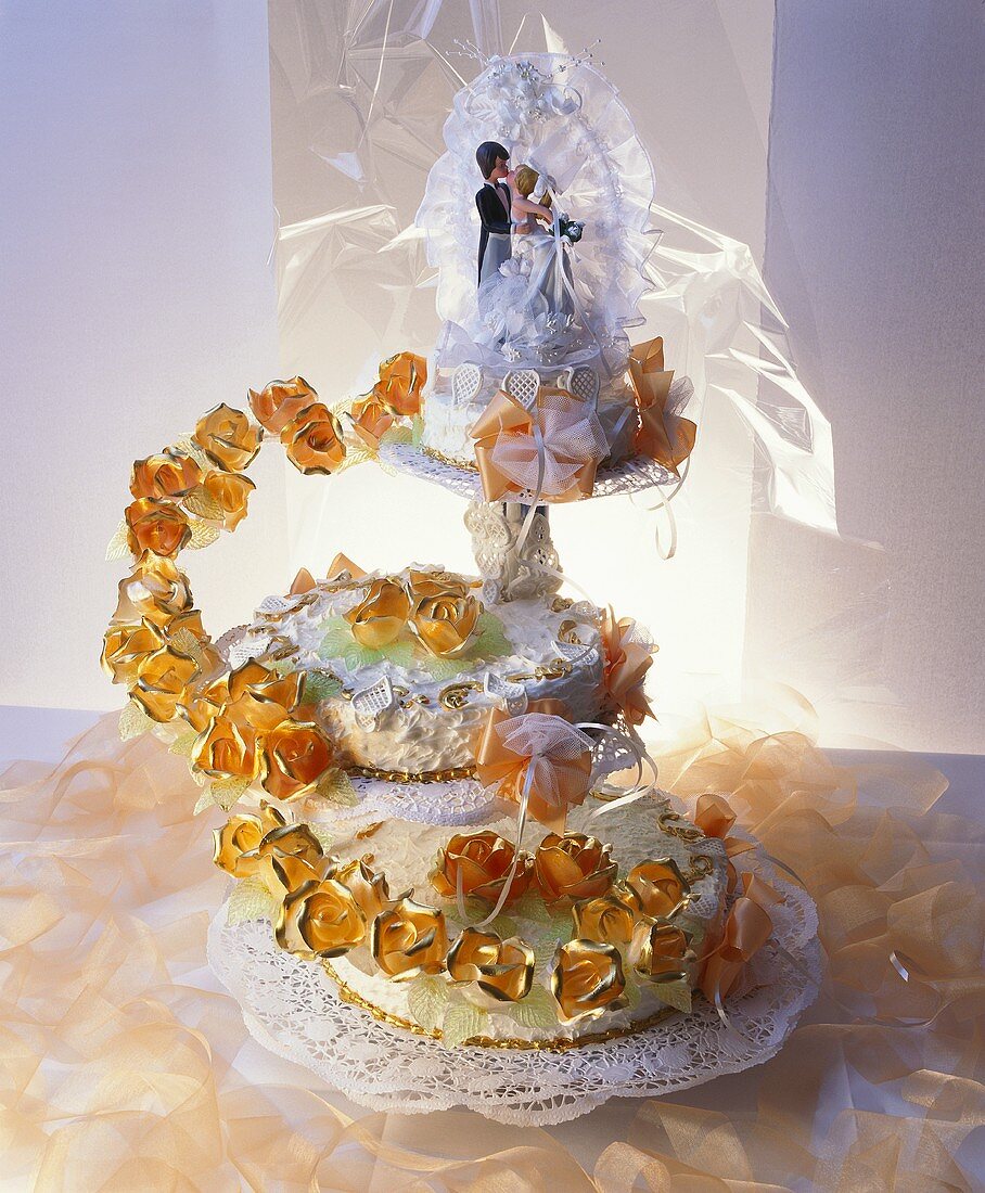 Three-tiered white wedding cake with bride & groom figures