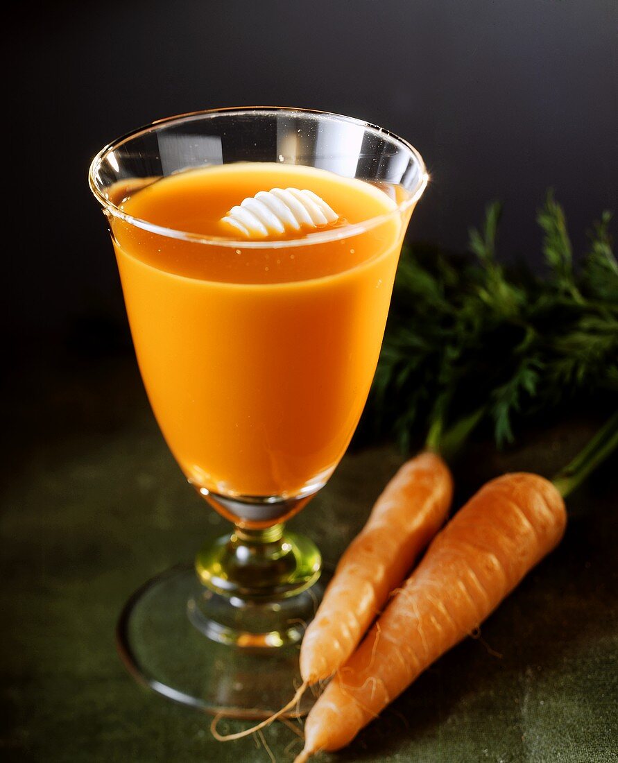 Ein Glas Karottensaft mit Butterröllchen