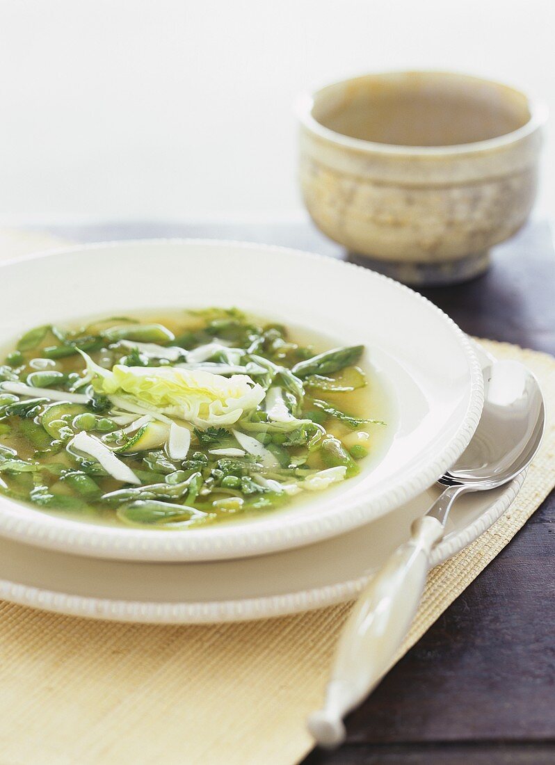 Clear asparagus soup with peas, courgettes and parmesan