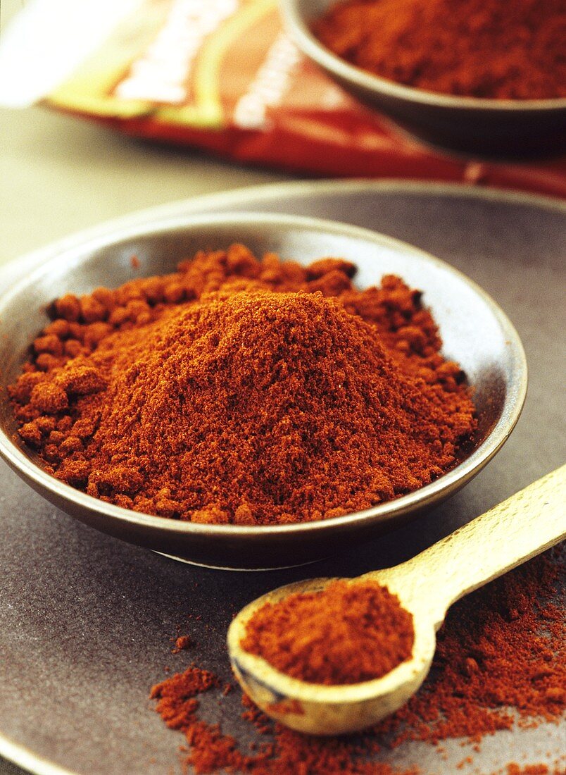 Paprika in a small bowl and on a wooden spoon