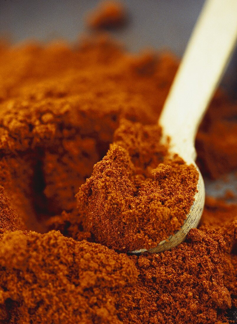 A heap of paprika with wooden spoon