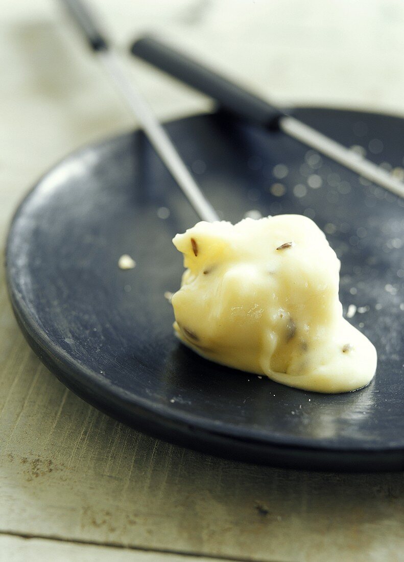 Kümmel-Käse-Fondue mit Brotstück auf Fonduegabel