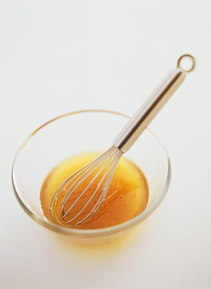 Vinaigrette in glass bowl with whisk