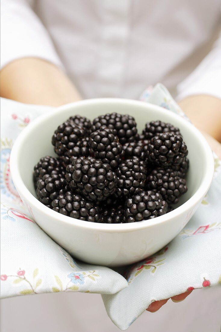 Woman holding bowl of blackberries