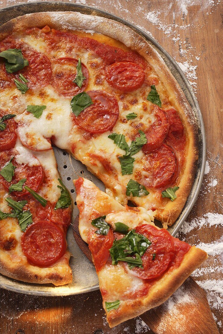 Pizza mit Tomaten, Käse und Basilikum, angeschnitten