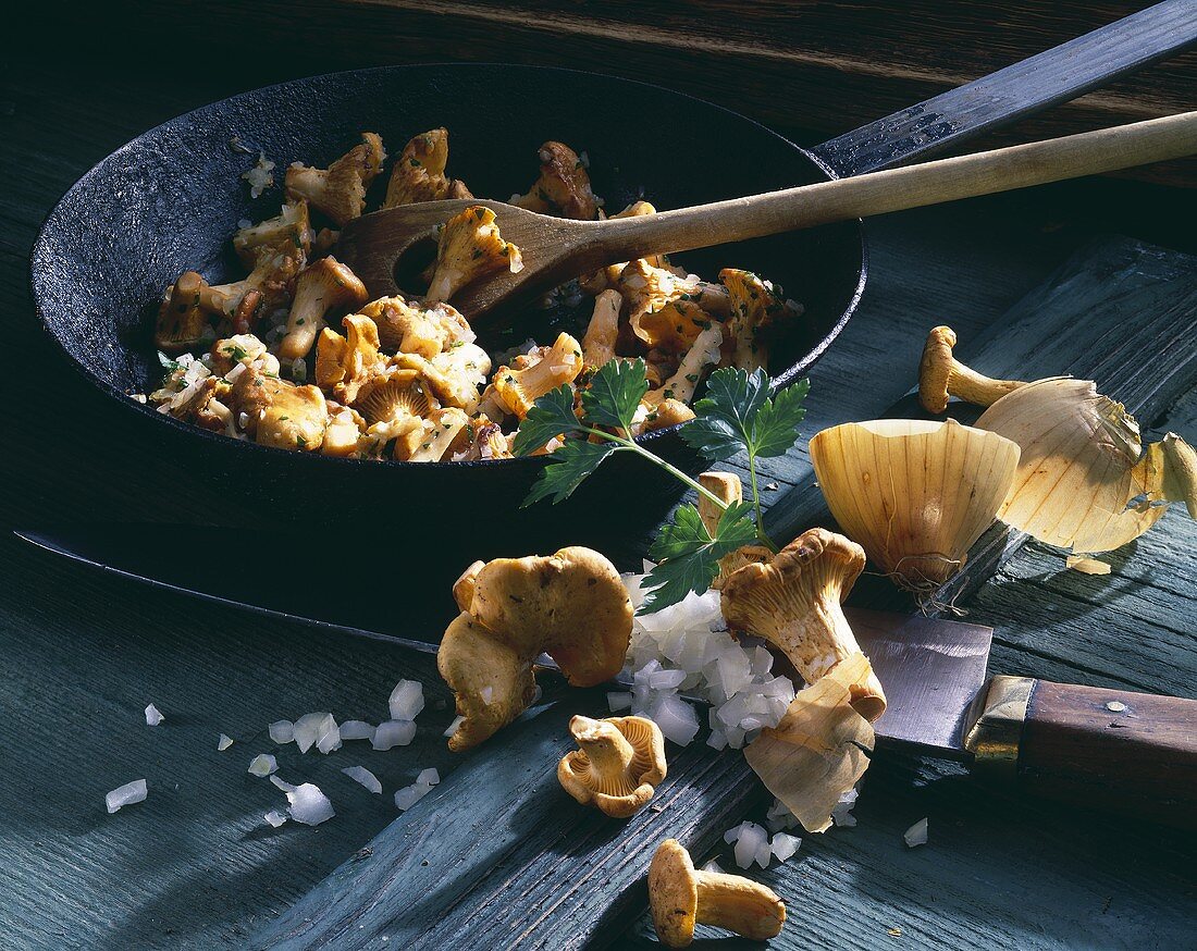 Fried chanterelles in frying pan, ingredients beside it