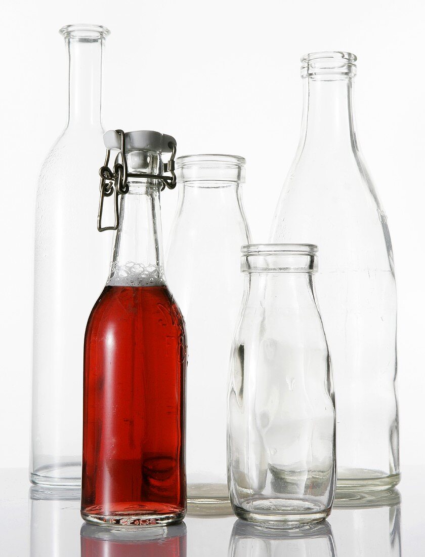 Bottle of cranberry juice and empty glass bottles