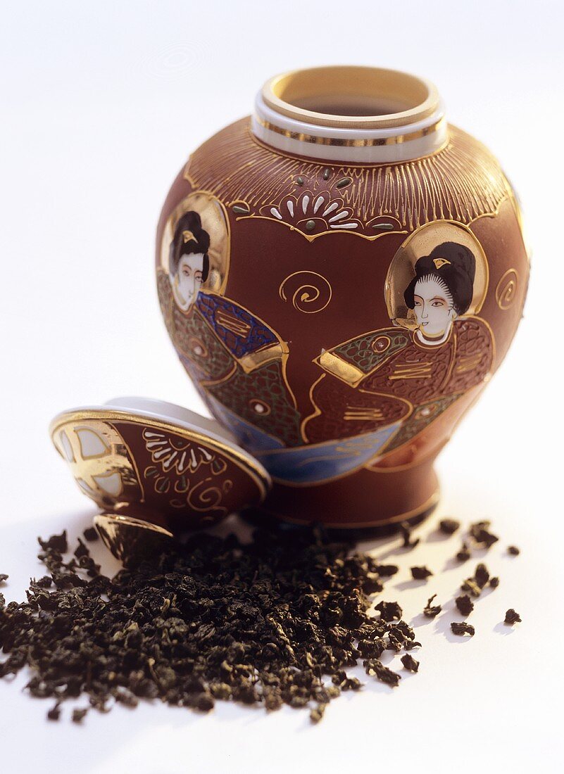 Ausgeschüttete Teeblätter vor dekorativer Teedose