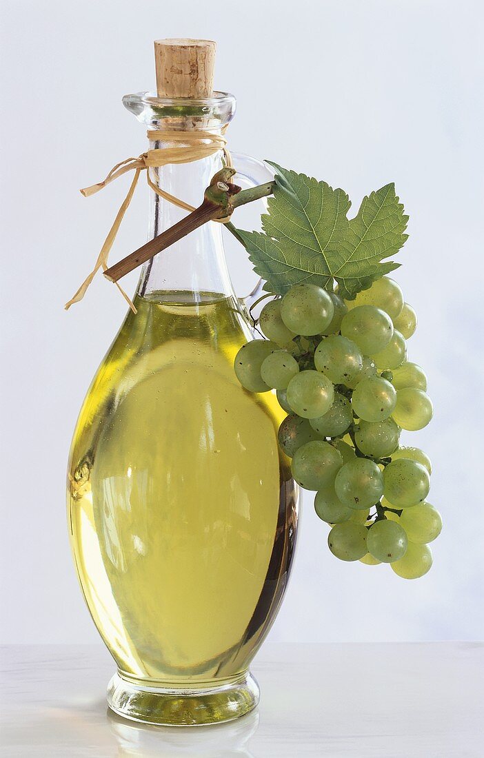 Grape seed oil in bottle with green grapes