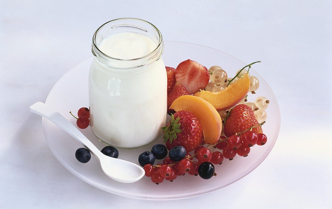 Glas Joghurt und frisches Obst auf Teller