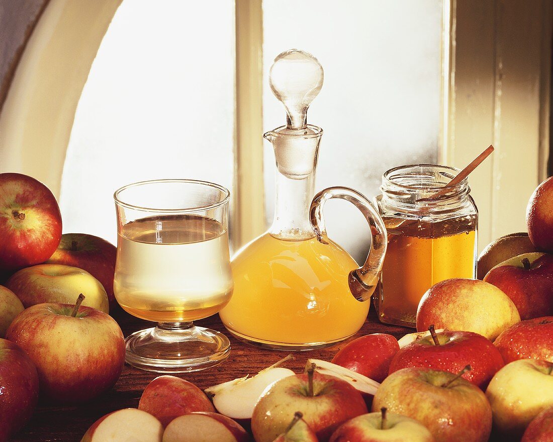 Stillleben mit Apfelessig, Honig und frischen Äpfeln