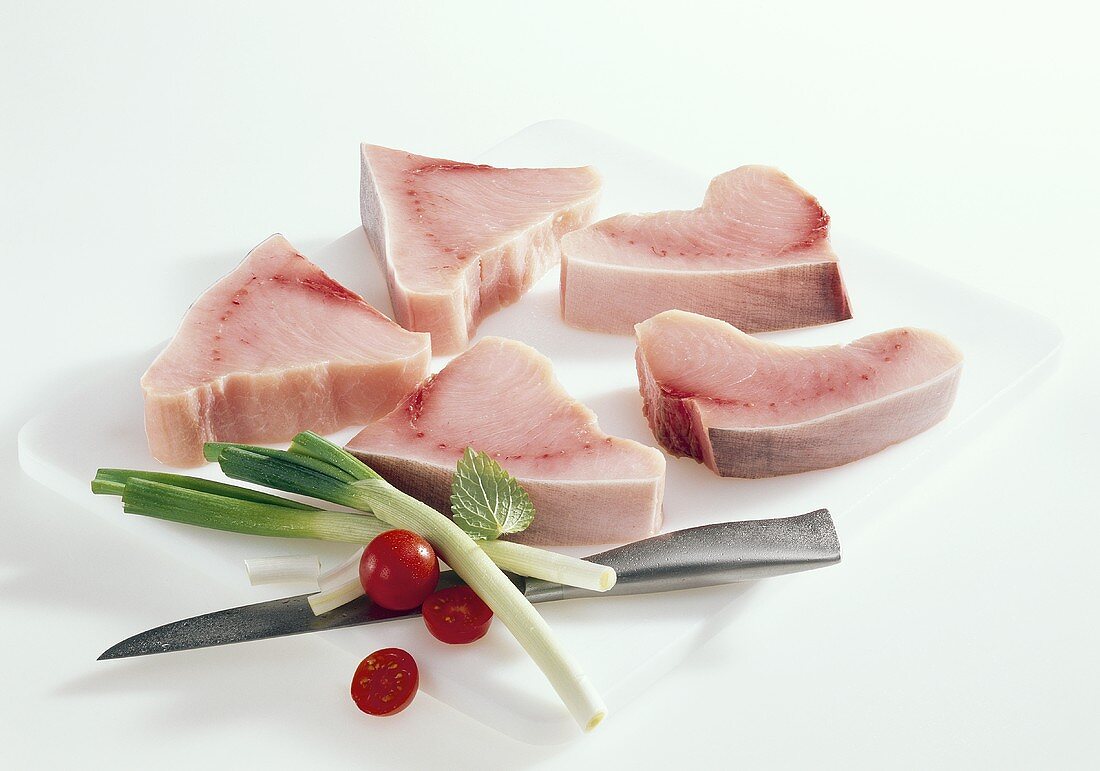 Swordfish fillets with vegetables on chopping board