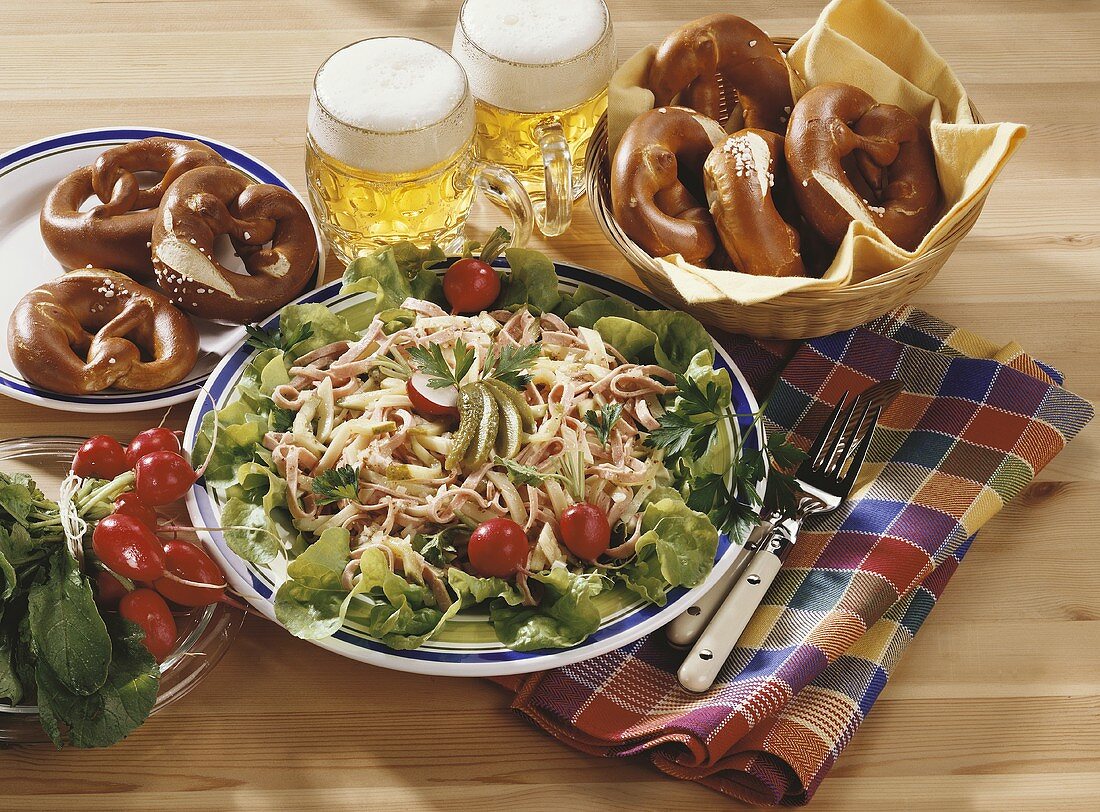 Hearty snack with sausage salad, pretzels and beer