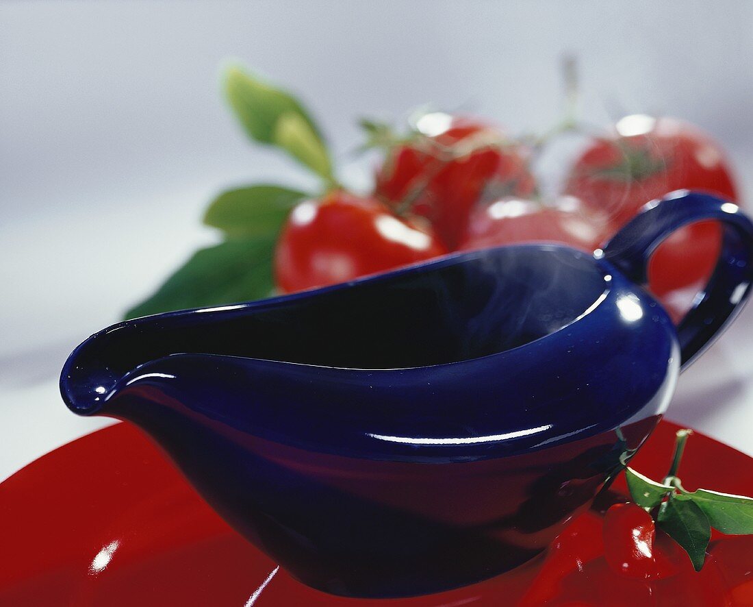 Warm sauce in blue sauceboat in front of red cherries