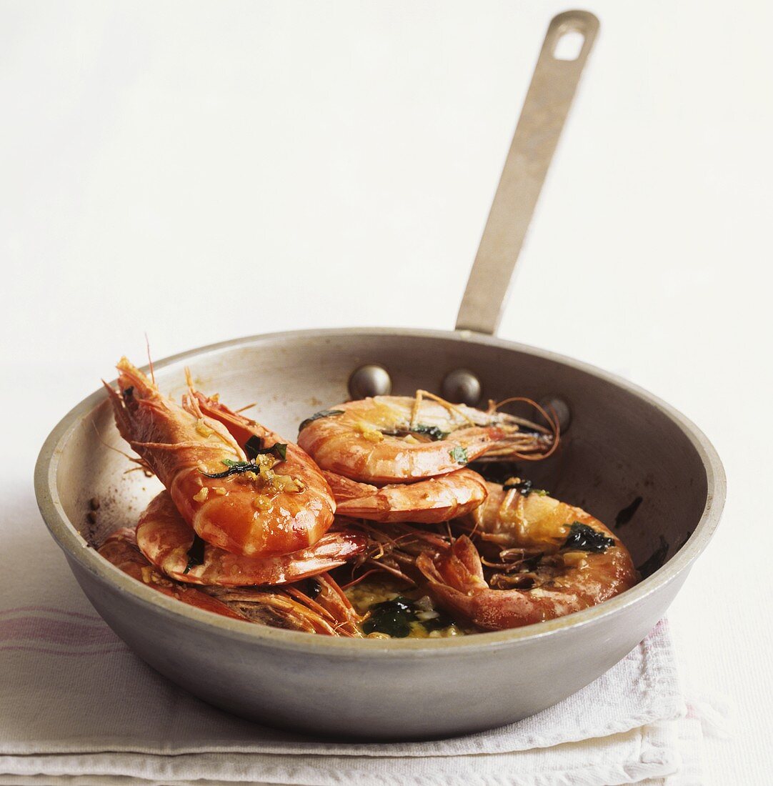 Garlic shrimps with herbs in frying pan