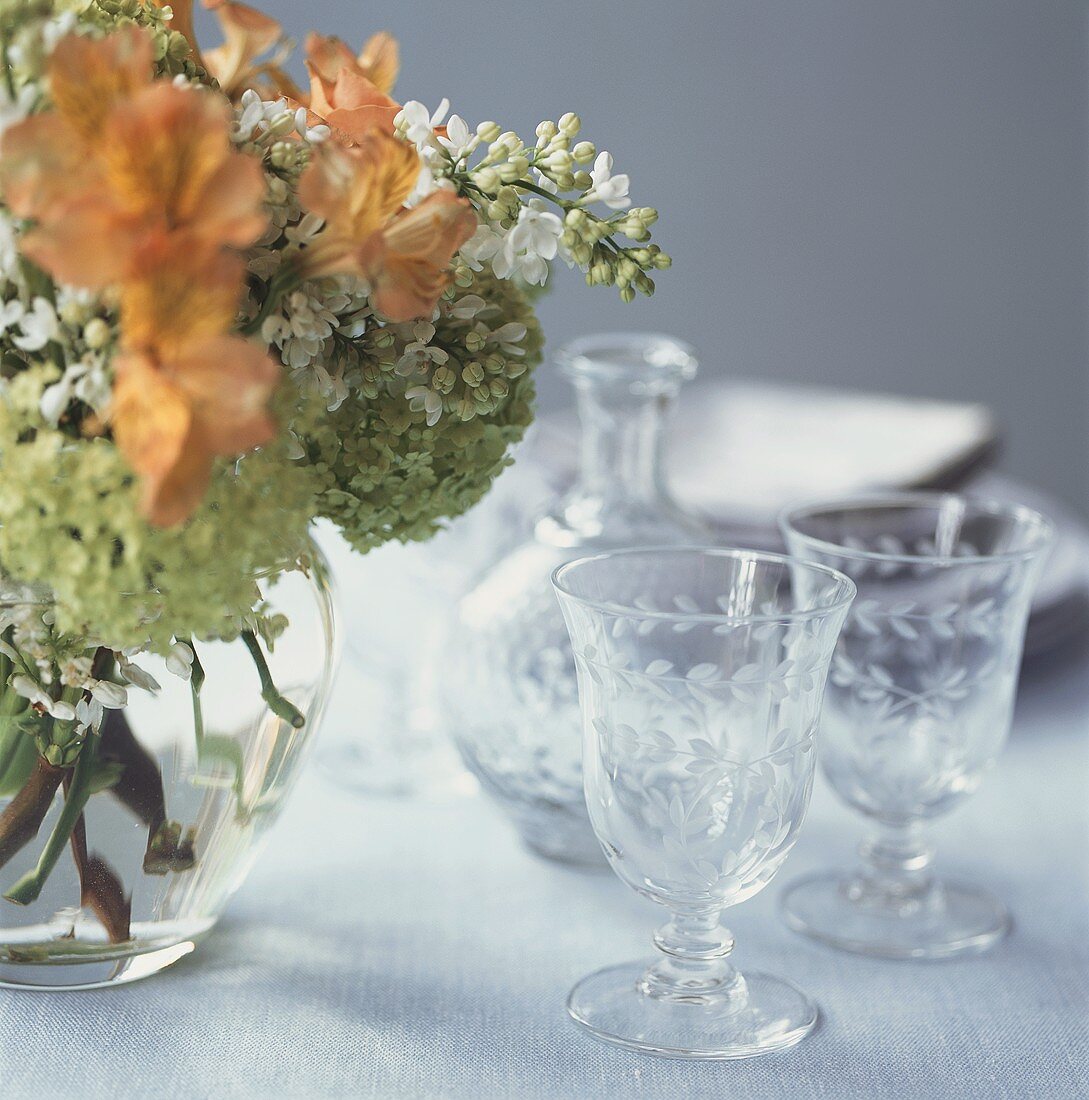 Empty wine glasses, carafe and flowers on table