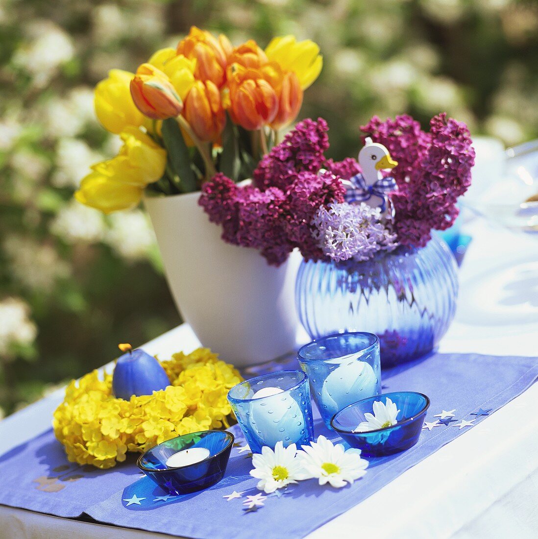 Deko mit Blumen und Kerzen für den Ostertisch im Freien